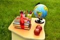 The books are tied with a red gift ribbon next to a globe, multi-colored felt-tip pens and two red apples are on the student`s tab Royalty Free Stock Photo