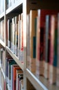 Many colorful Books on a white bookshelf in a public library room.