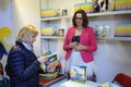 Bookseller standing behind a bookstore counter and telling customer about books available Royalty Free Stock Photo