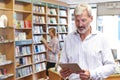 Male Bookstore Owner Using Digital Tablet With Customer In Background Royalty Free Stock Photo