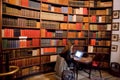 Bookstore with student working under laptop, and many vintage science books on shelves