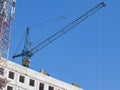 The Boom of a Cargo Tower Crane Rises Above the Roof of a Multi-Storey Building Under Construction Royalty Free Stock Photo