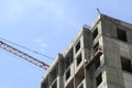 The boom of a construction crane over building under construction against a background of a bright blue sky Royalty Free Stock Photo