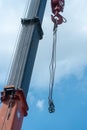 Boom of a tower crane in close-up against the blue sky. A working crane on a construction site. View of the crane hook, cables and