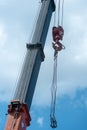 Boom of a tower crane in close-up against the blue sky. A working crane on a construction site. View of the crane hook, cables and Royalty Free Stock Photo