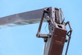 Boom of a tower crane in close-up against the blue sky. A working crane on a construction site. View of the crane hook, cables and