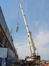 The boom of the truck crane lifts the equipment of the air conditioning system to the roof of the warehouse