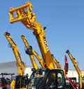 Booms of JCB excavators and telehandlers against blue sky in the official dealership