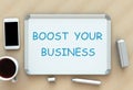 Boost Your Business, message on whiteboard, smart phone and coffee on table Royalty Free Stock Photo
