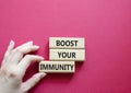 Boost your immunity symbol. Concept word Boost your immunity on wooden blocks. Doctor hand. Beautiful red background. Helthcare