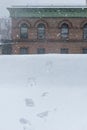 Boot-prints leading toward the edge of a rooftop during heavy snowfall