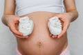 Booties for newborn in the hands of a pregnant girl on the background of the abdomen Royalty Free Stock Photo