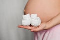 Booties for newborn in the hands of a pregnant girl on the background of the abdomen Royalty Free Stock Photo