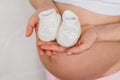 Booties for newborn in the hands of a pregnant girl on the background of the abdomen Royalty Free Stock Photo