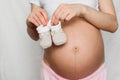 Booties for newborn in the hands of a pregnant girl on the background of the abdomen Royalty Free Stock Photo