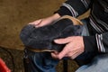 Bootmaker making shoes sitting in workshop. Shoemaker holding gray suede shoe in hands before stitching. Bespoke shoes