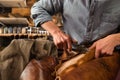 Bootmaker sitting in workshop making shoes