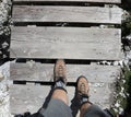 Boots of the adventurous hiker walking on the wooden bridge in mountains