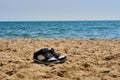 Boots on beach. Shoes on sand near sea. Lone sneakers. Black white sneakers. Royalty Free Stock Photo