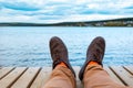 Boots on the feet of a resting person on the background of the lake