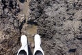 Boots in the mud. The feet of a man shod in white waterproof boots made of ethylene vinyl Acetate stand in the brown sucking mud.