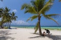 Boracay, Malay, Aklan, Philippines - A couple relaxing by a coconut tree in White Beach, one of the most popular