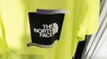 The North Face text sign and logo brand of fashion clothes in yellow shirt in store