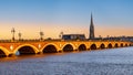 Bordeaux, France. View of Pont de Pierre, old stone bridge over the river Garonne, and Saint Michel cathedral at sunset. Royalty Free Stock Photo