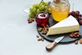 Border of brie or camembert cheese on plate slate on gray wooden background with nuts, grapes, honey and cherry jam. Italian food Royalty Free Stock Photo