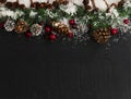 Border of Christmas snow, fir tip branches, red berries and silver gold pine cones on dark stone setting Royalty Free Stock Photo