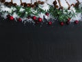 Border of Christmas snow plus fir tip branches and red berries on dark stone setting Royalty Free Stock Photo