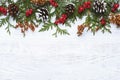 Border of Christmas tree branches pine cones flowers and red berries on white wooden background, copy space Royalty Free Stock Photo