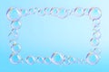 Iridescent soap bubbles forming a decorative frame against a soft blue gradient background Royalty Free Stock Photo