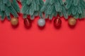 Border from decorative spruce branches with Christmas balls on a red textured paper background. Top view, flat lay, copy Royalty Free Stock Photo