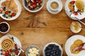 A border of delicious breakfast plates, pancakes and pasteries, bowls of fruit and porridge, and cups of coffee, on a rustic Royalty Free Stock Photo