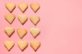 Border of homemade heart shaped cookies on pink. Flat lay