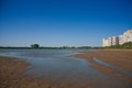 Border of a large multi-story city and countryside. tall houses on the banks of a shallow river. the concept of urban expansion