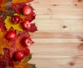 Border made of autumn maple leaves and red apples over wooden background with copy space Royalty Free Stock Photo