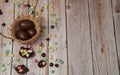 The border is made of an egg hunter`s basket and multicolored chocolate eggs on a light wooden background. Royalty Free Stock Photo