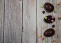 The border is made of multicolored chocolate eggs on a light wooden background. Royalty Free Stock Photo