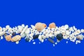 Border made of shells, pebbles and stones on a blue background Royalty Free Stock Photo