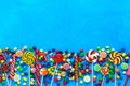 Border of multicolored candies, round colorful candy and jelly on a blue background. Top view, flat lay, copy space