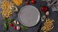 Border of raw pasta durum wheat, tomato sauce, cherry tomatoes, basil and garlic on dark gray. Top view. Flatlay style Royalty Free Stock Photo