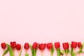 Border of red tulips on pink background. Mothers day, Valentines Day, Birthday celebration concept. Copy space, top view