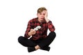 Bored adolescent boy seated on the floor playing video games isolated over white background. Sleepy boy holding joystick console, Royalty Free Stock Photo