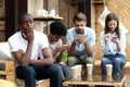 Bored African American man sitting with people with phone depend