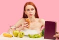 Bored apathetic woman eats croissant staring off into space ignoring raw fruits Royalty Free Stock Photo