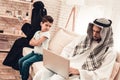 Bored Arabian Boy Sitting with Family on Sofa