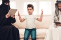 Bored Arabian Boy Sitting with Family on Sofa.