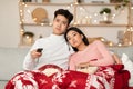 Bored Asian Couple Watching TV Celebrating Christmas At Home Royalty Free Stock Photo